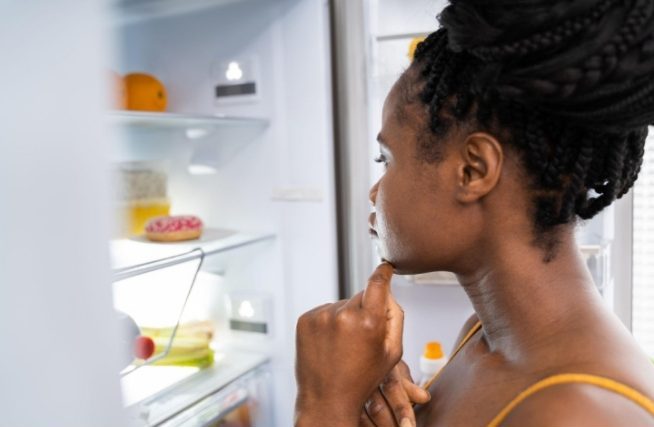 Woman looking into her refrigerator while deciding what to eat
